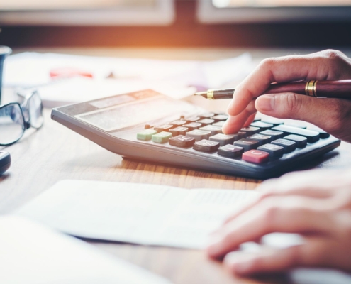 Business Person At Desk Typing On Calculator