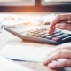 Business Person At Desk Typing On Calculator